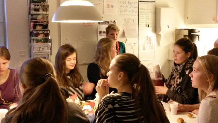 En gruppe unge piger sidder sammen i en køkken.