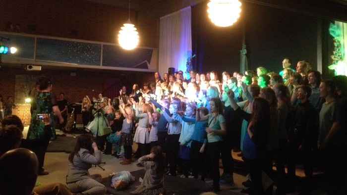 En gruppe af mennesker danser og festet i en mørk scene med blå lys.