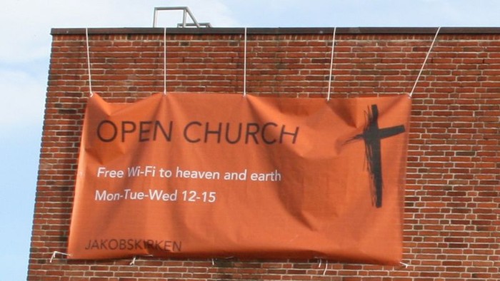 Rød banner på kirke med invitasjon til gratis Wi-Fi.