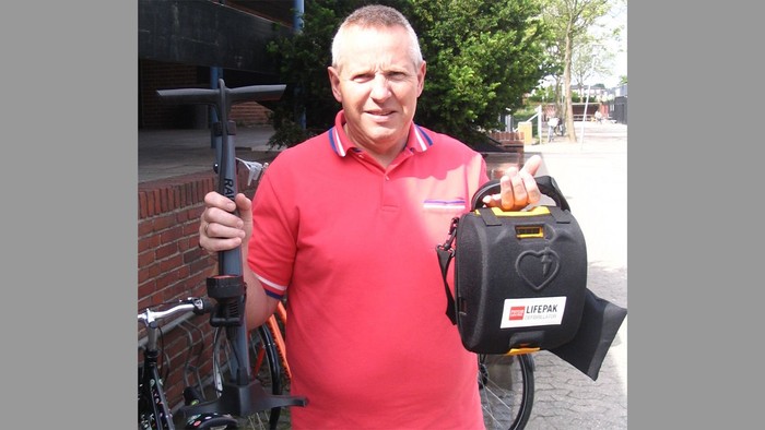 Mand i rød polo holdet en cykel og en kaffemaskine.