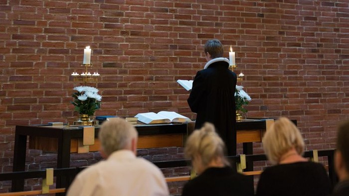 En præst holder en tale under en gudstjeneste i en kirke.