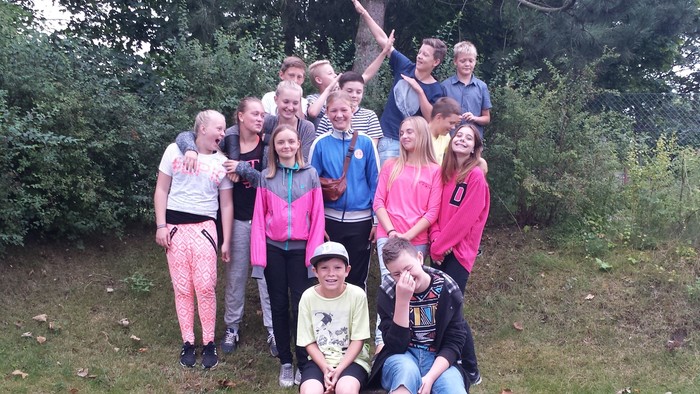 En gruppe af unge står sammen i en park og smiler til kameraet
