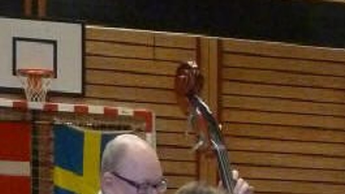 En gruppe musikere spiller i en sportshal