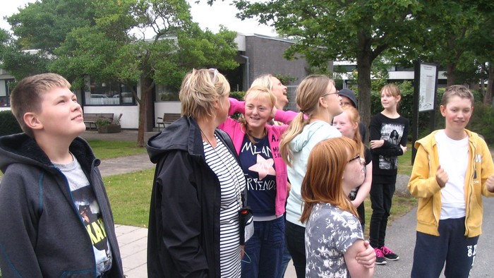 En gruppe unge og voksne står sammen ude og snakker.