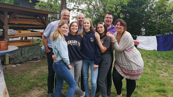 Eine Gruppe von Menschen posiert vor einem Baum und einem Schuppen