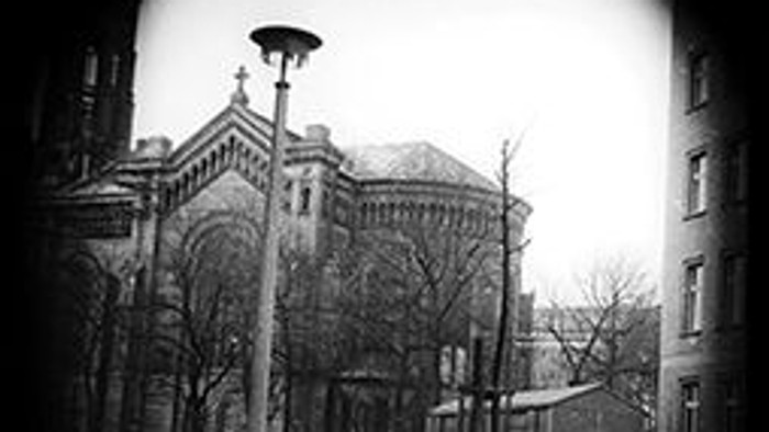 Schwarze und weiße Fotografie einer Stadtstraße mit Autos und Laternenpfahl