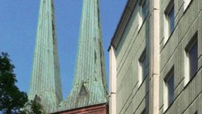 Zwei hohe Kirchtürme neben einem modernen Gebäude