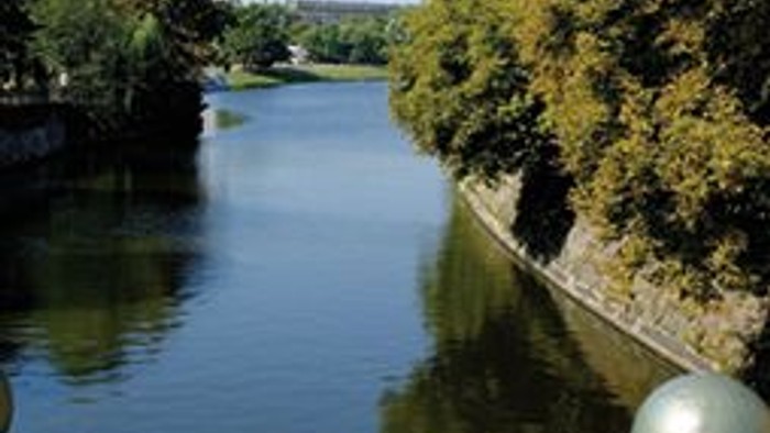 Ein ruhiger Fluss mit Bäumen und einer Brücke, auf der