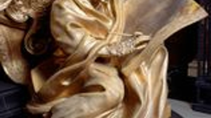 Goldene Engelsfigur mit großem Band auf schwarzer Oberfläche