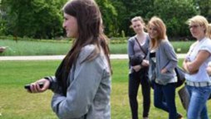 Eine Gruppe von Jugendlichen steht im Park und unterhält sich.
