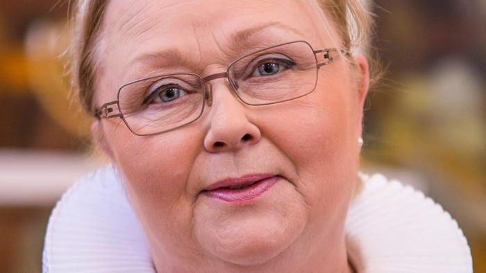 En kvinde med hvid krage og briller.