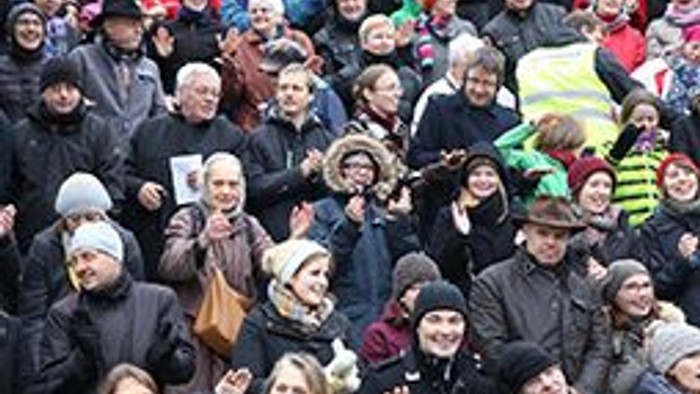 Eine große Gruppe von Menschen feiert gemeinsam, viele tragen Weihnachtsmützen und Accessoires.
