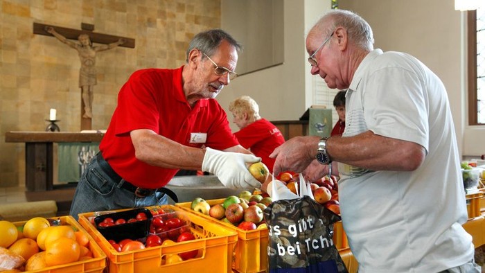 Zwei ältere Männer sortieren gemeinsam Obst in einer Kirche