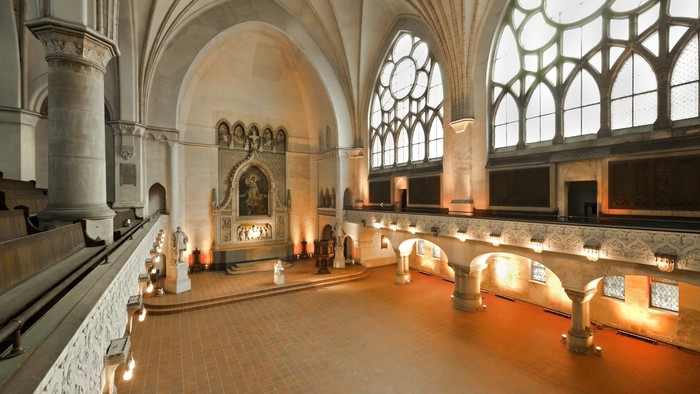 Großzügige Kirchenhalle mit hohen Bögen und bunten Glasfenstern