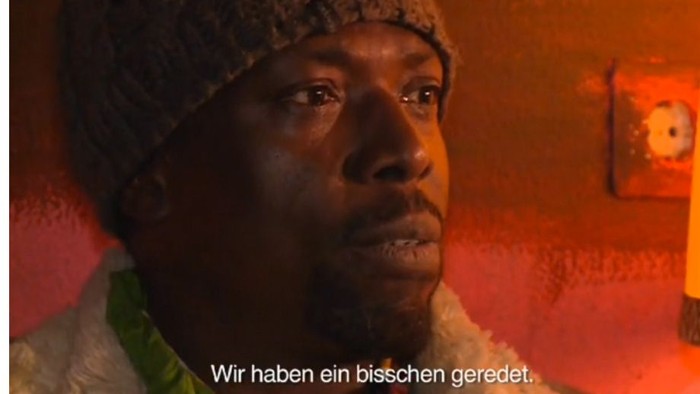 Ein Mann mit Mütze schaut traurig in die Kamera, Text: