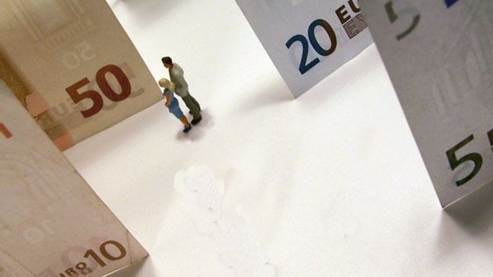 Kleine Figur steht zwischen Euro-Scheinen