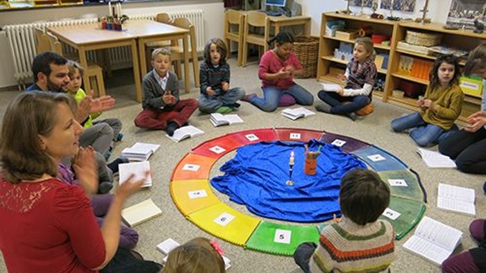 Eine Gruppe von Kindern sitzt im Kreis auf dem Boden und spielt ein Spiel.