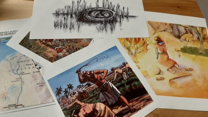 Verschiedene Kunstwerke und eine Karte liegen auf einem Holztisch