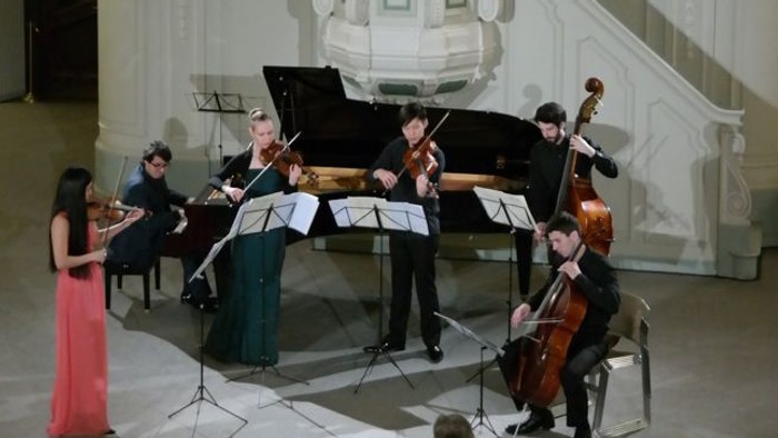 Eine Gruppe von Musikern spielt in einem großen, hell erleuchteten Saal.