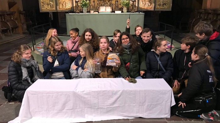 En gruppe børn poserer sammen ved en altertavle i en kirke.