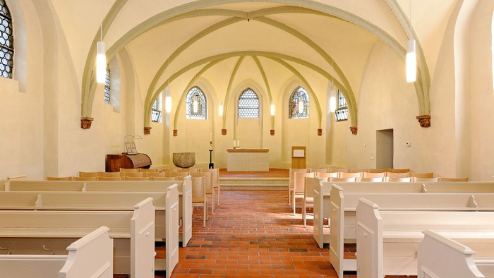 Die Kirche hat weiße Bänke und hohe Decken mit Rundbogenfenstern.