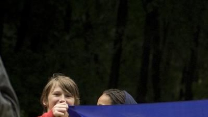 Eine Gruppe von Menschen hält ein großes Regenbogenbanner mit der Aufschrift