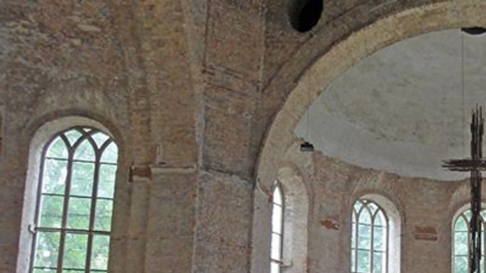 Alte Kirche mit Holzbänken und hohen Fenstern