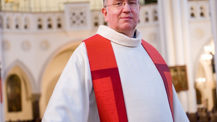 Mann in weiß-roter Soutane vor Kirchenorgel