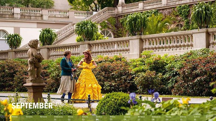 Ein Paar tanzt in einem Garten, umgeben von Blumen und einem Brunnen, im September