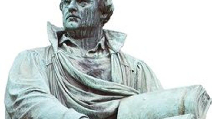 Die Statue eines Mannes mit Buch und Umhang.