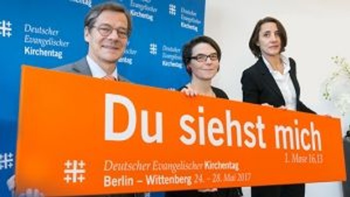 Drei Personen halten ein Schild mit der Aufschrift