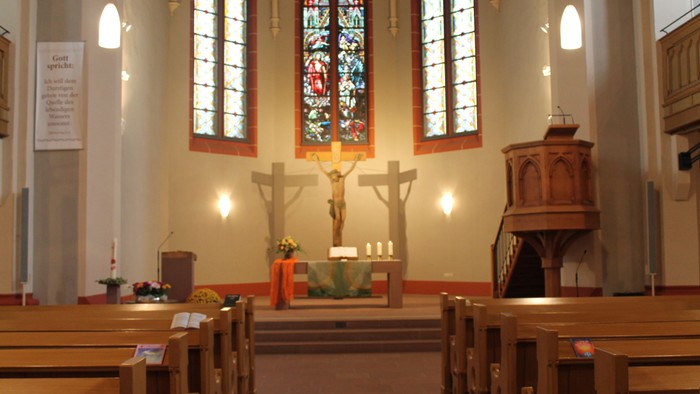 Innenraum einer Kirche mit Altarraum und Buntglasfenster
