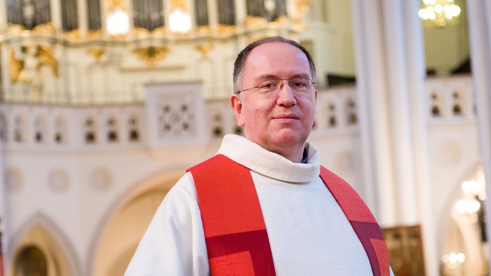 Mann in weiß-roter Soutane vor Kirchenorgel