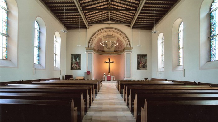 Leere Kirche mit Holzbänken und Altarraum