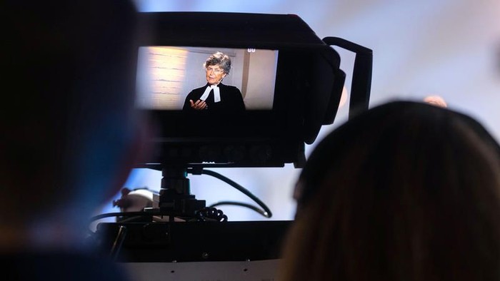 Eine Person, die eine Live-Übertragung oder ein Interview mit einer auf einem Stativ montierten Kamera filmt.