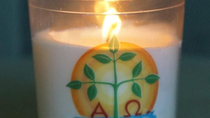 Eine brennende Kerze in einem Glas mit einem Baum-Design.