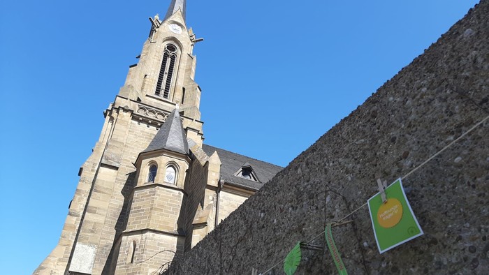 Kirchturm mit grünen Fahnen an Steinmauer