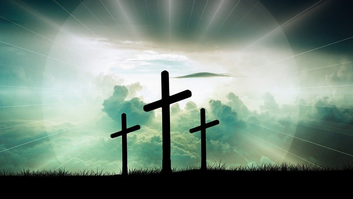 Drei Kreuze vor hell erleuchtetem Himmel