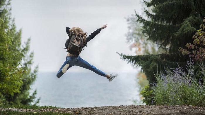 En person udfører et spring i naturen ved en sø.