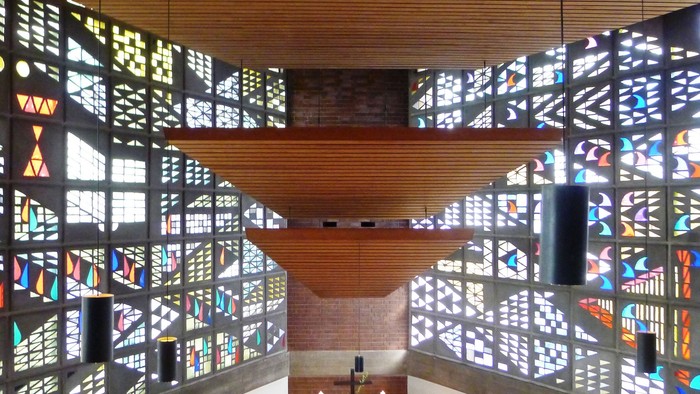 Modernes Kircheninnere mit farbenfrohen Buntglasfenstern und Holzdecke