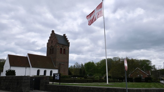 En kirke med tårn og en flagstang med flag ved siden af.