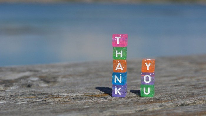 Bunte Holzklötze bilden Dankeschön-Nachricht am Strand