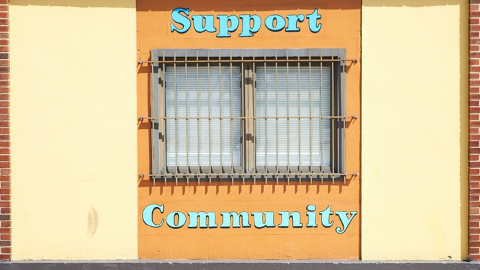 Das Bild zeigt ein Gebäude mit einem Fenster und zwei Schildern: 