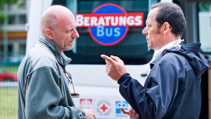 Zwei Männer unterhalten sich vor einem Beratungsbus.