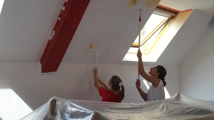 Zwei Personen streichen eine Decke weiß