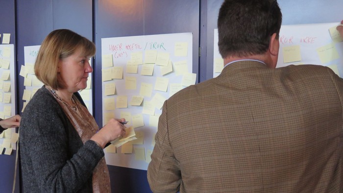 To folk arbejder med brainstorming på papirer på væggen