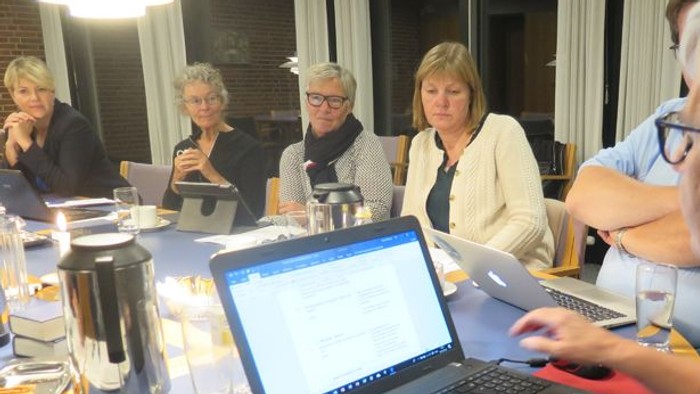 En gruppe kvinder sidder ved et bord med laptoper og drikkevarer.