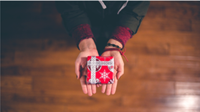Hands holding red and white gift box with ribbon.