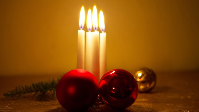 En lyse julelyst med tre lysende lygter og tre røde glaskugler på bord.