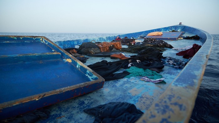 Ein blaues Boot mit verschiedenen Taschen und Kleidungsstücken auf dem Meer.